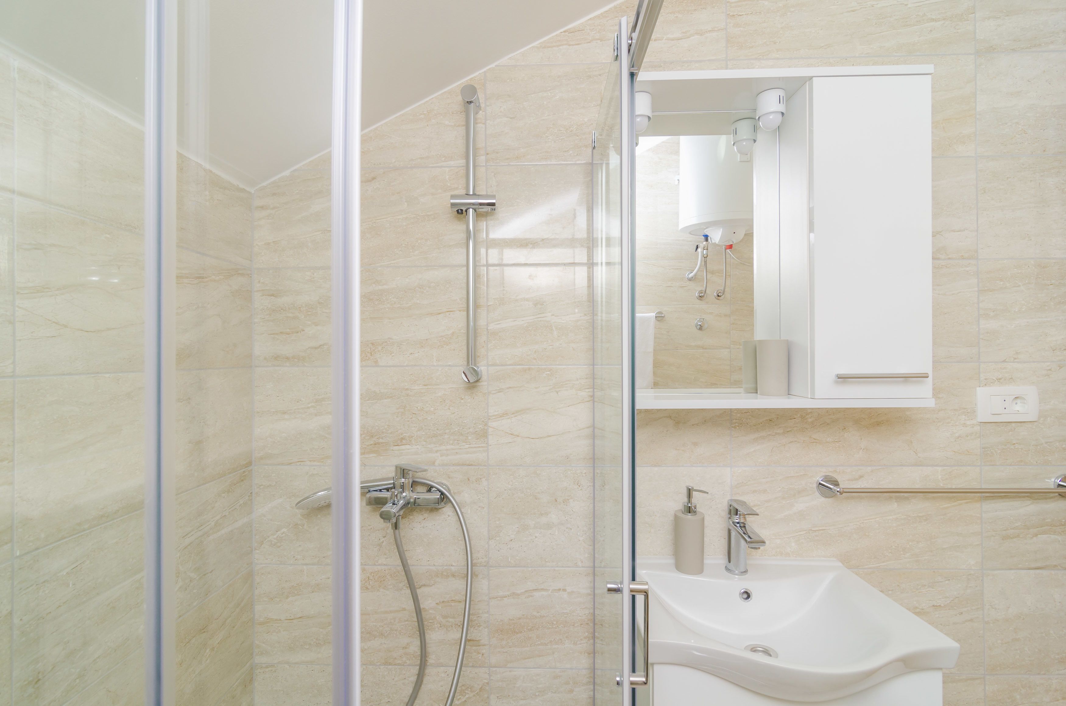A modern bathroom with a glass shower enclosure, a white sink, and a mirror above the sink.