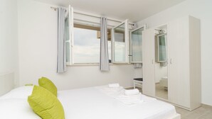 A bedroom with a bed, a wardrobe, and a window with curtains. - Apartments Villa Dadic (Dubrovnik)