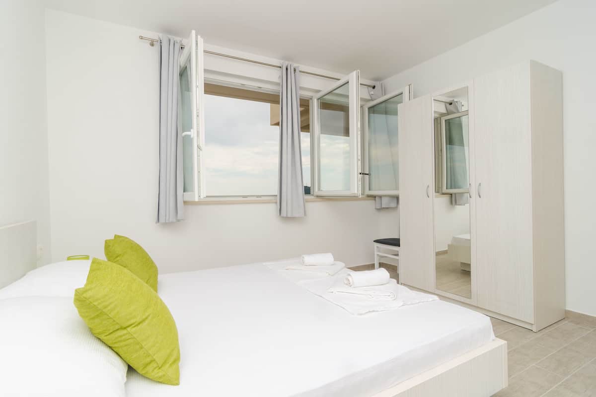 Een slaapkamer met een bed, een kledingkast en een raam met gordijnen.