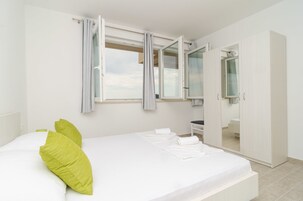 Un dormitorio con cama, armario y ventana con cortinas.