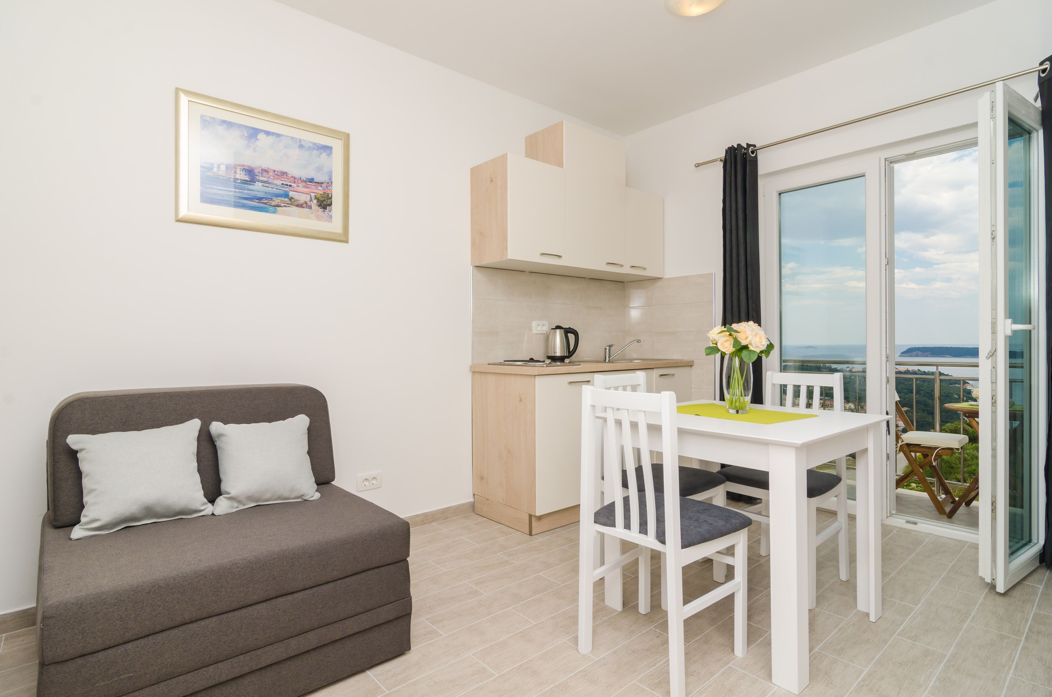 A modern apartment with a balcony, a kitchenette, a dining area, and a sofa.
