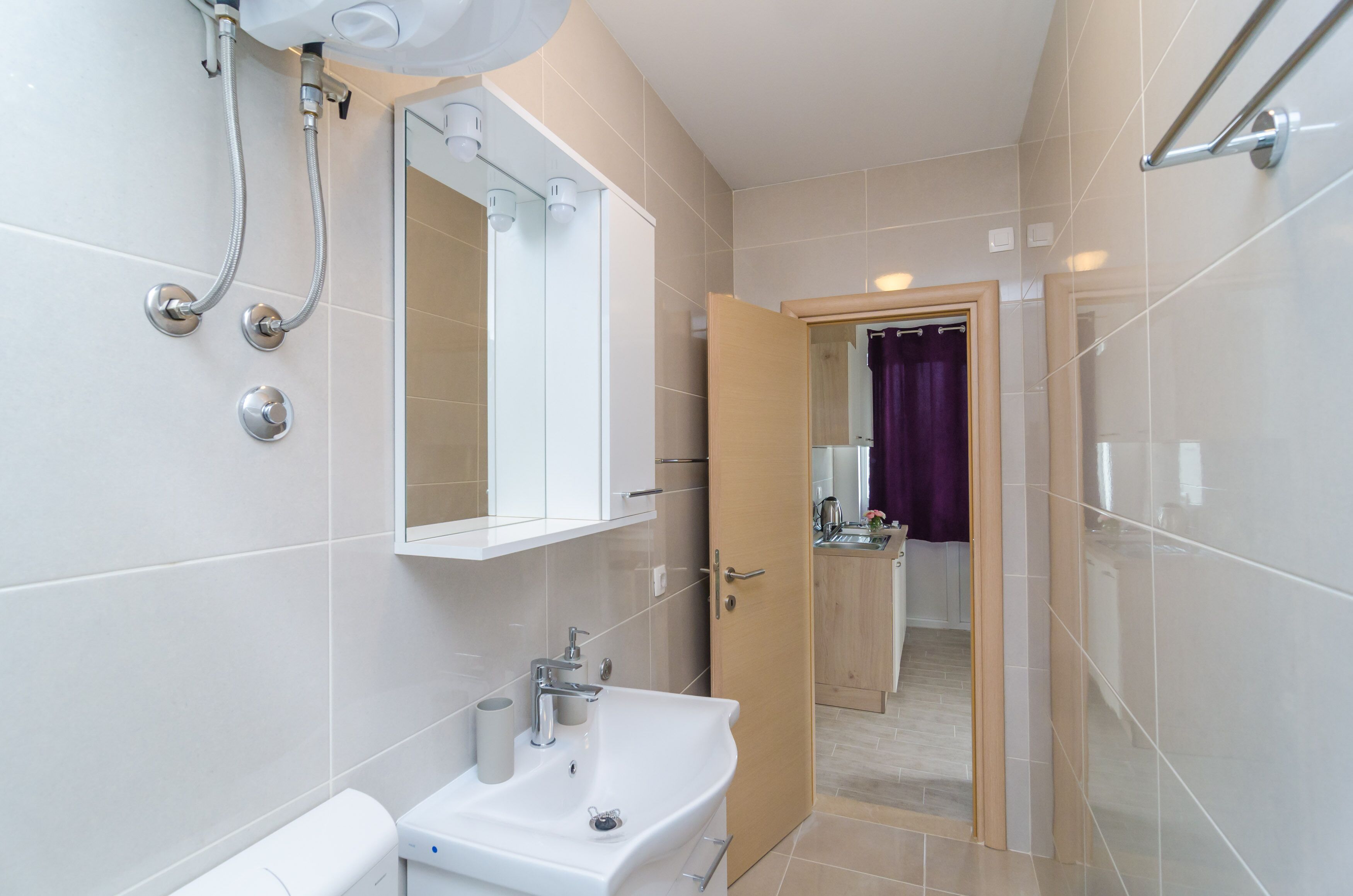 A modern bathroom with a white sink, mirror, and shower.