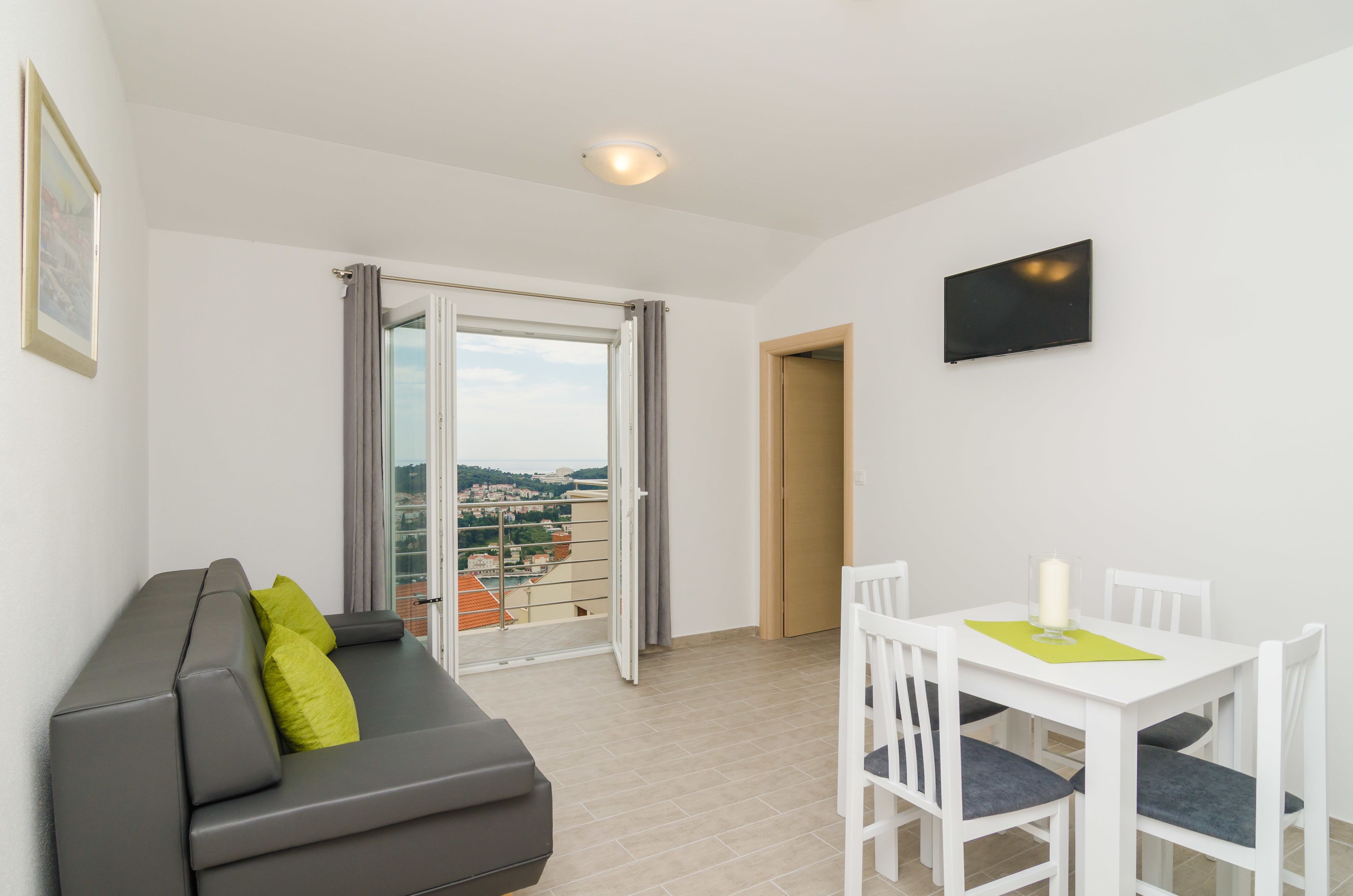 A modern apartment with a balcony, a dining area, and a sofa with cushions.