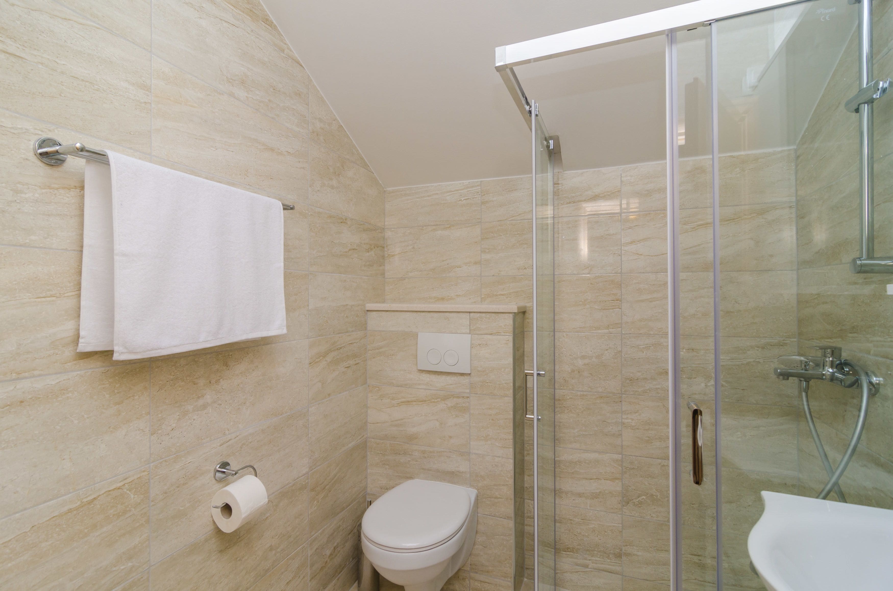 A bathroom with a glass shower enclosure, a toilet, and a sink.