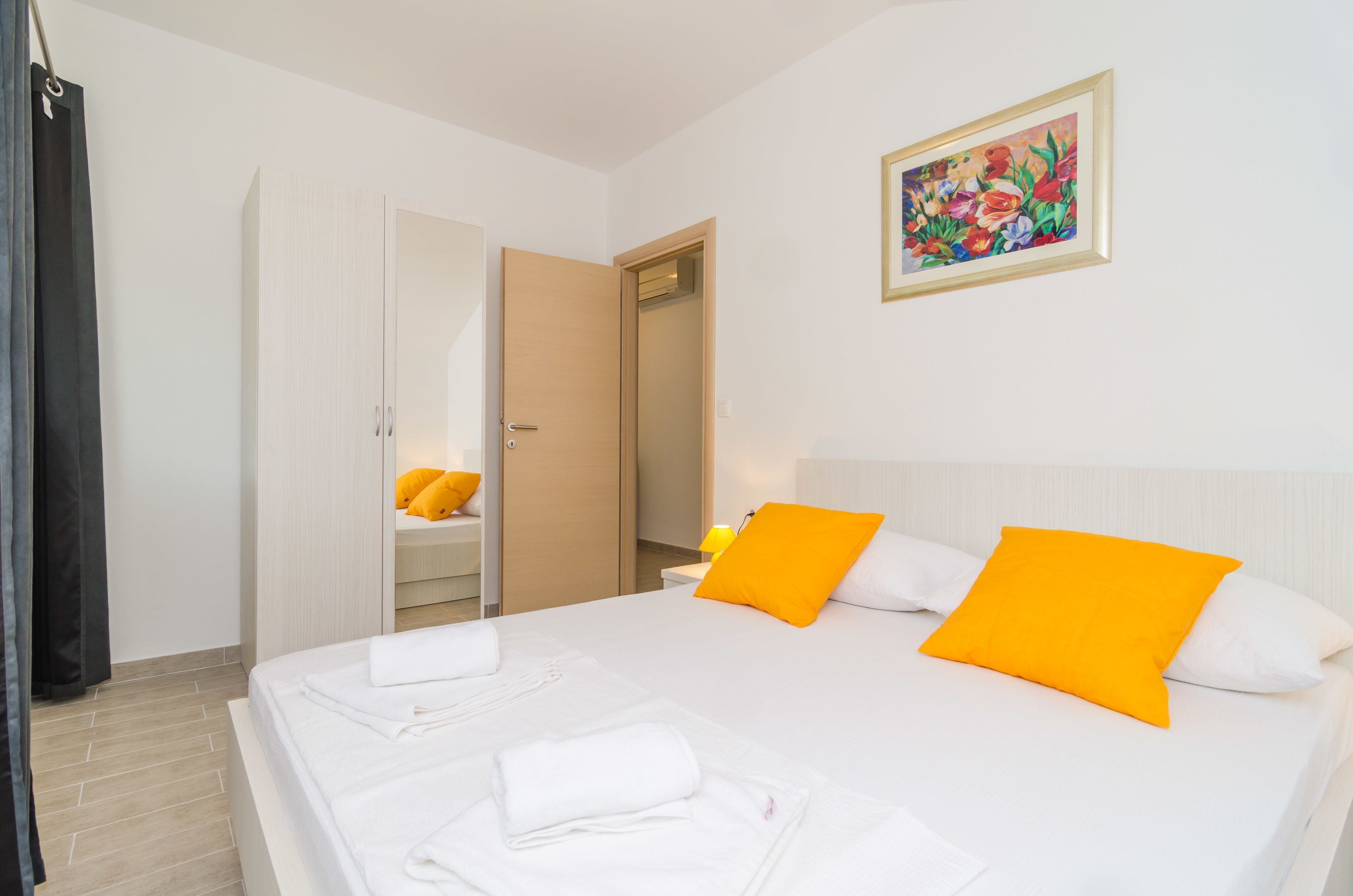 Une chambre d’hôtel avec un lit, deux oreillers, une table de chevet, une lampe, une armoire et un tableau au mur.