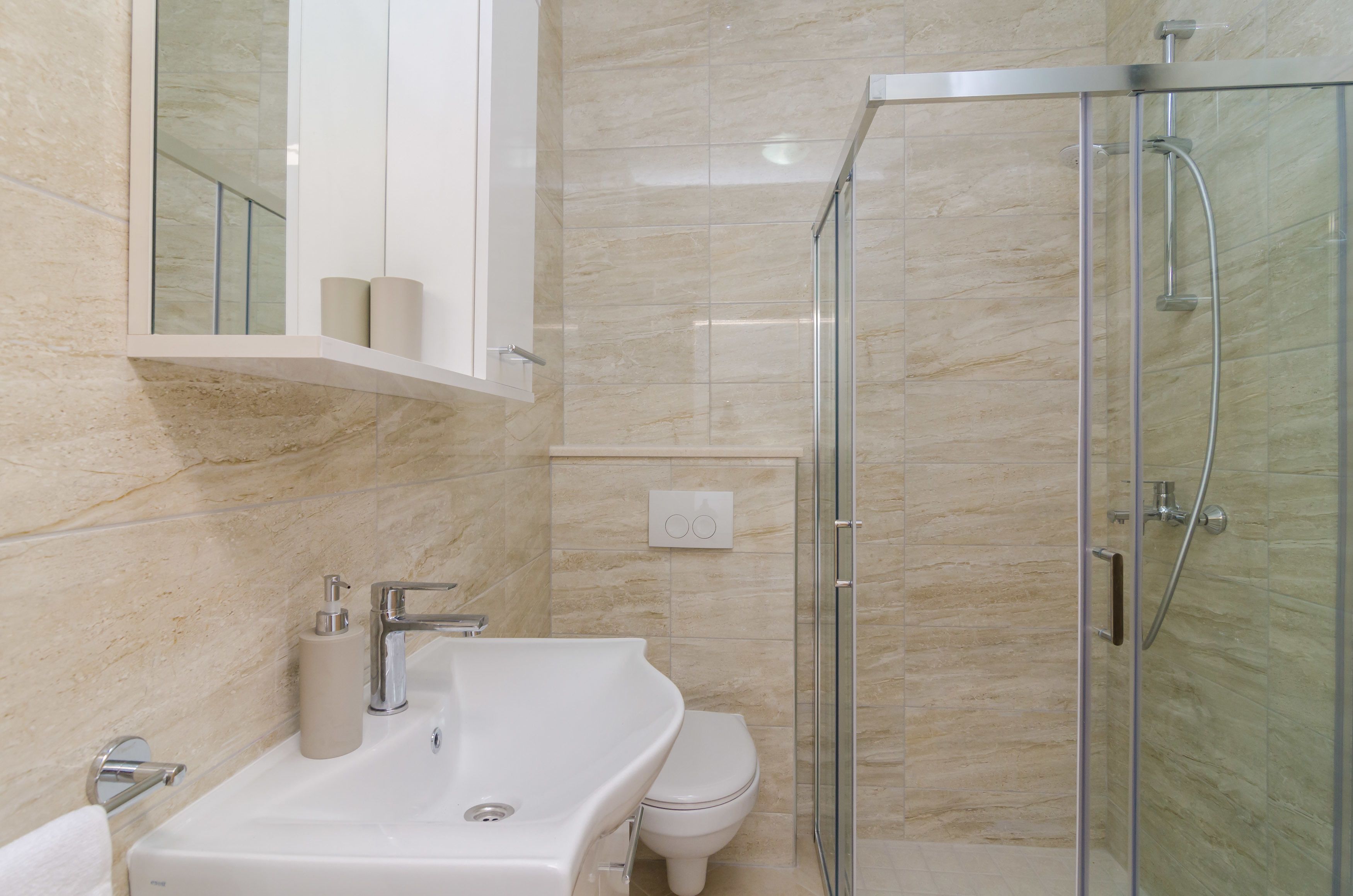 A modern bathroom with a glass-enclosed shower, a white sink, and a toilet.