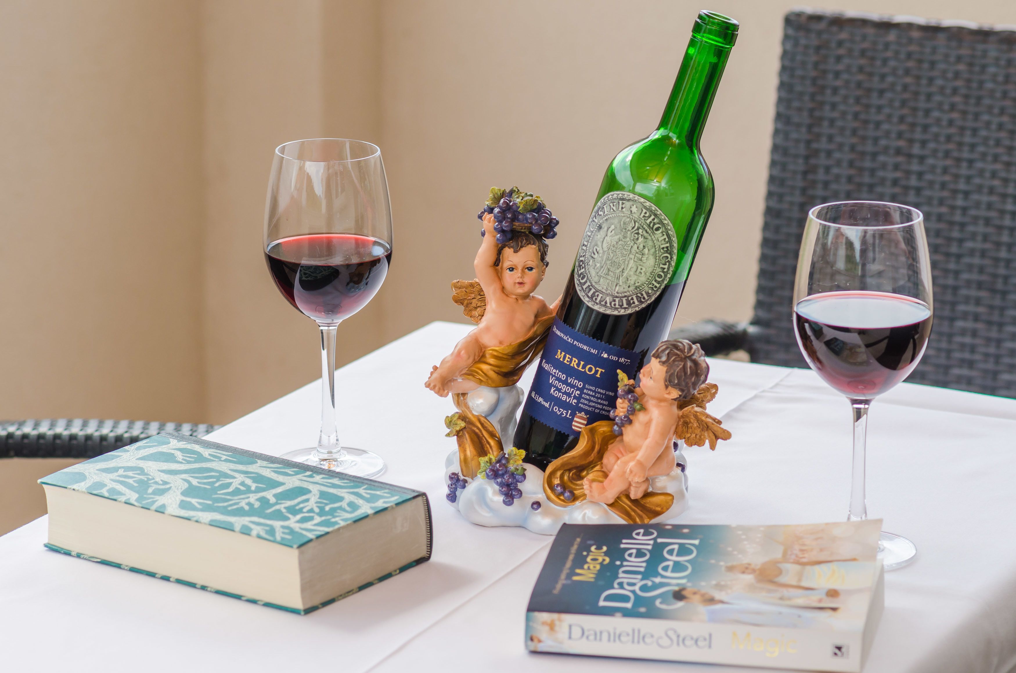 A table with a book, a wine bottle, and two wine glasses.