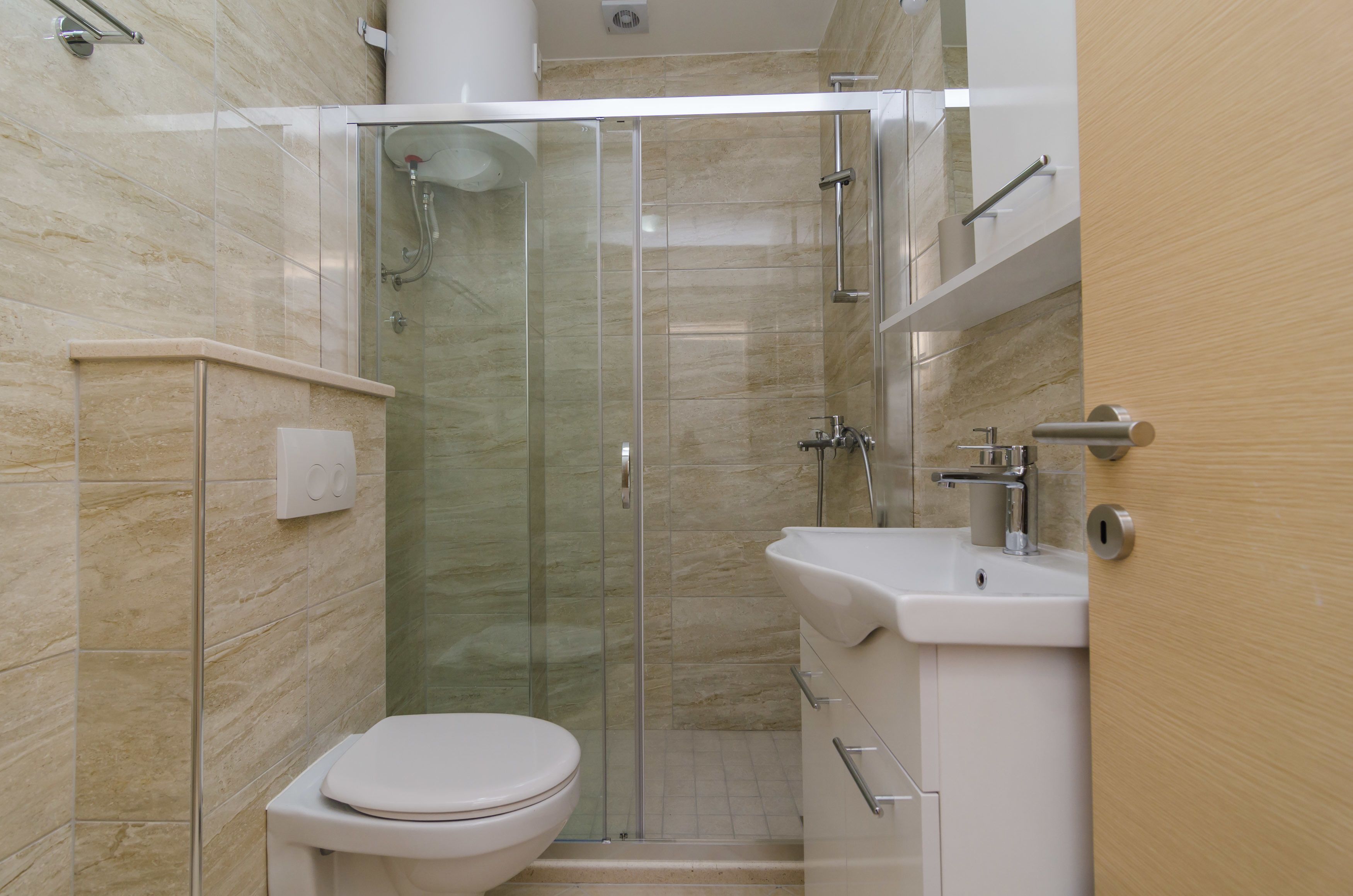 A modern bathroom with a glass-enclosed shower, a white toilet, and a sink with a mirror.
