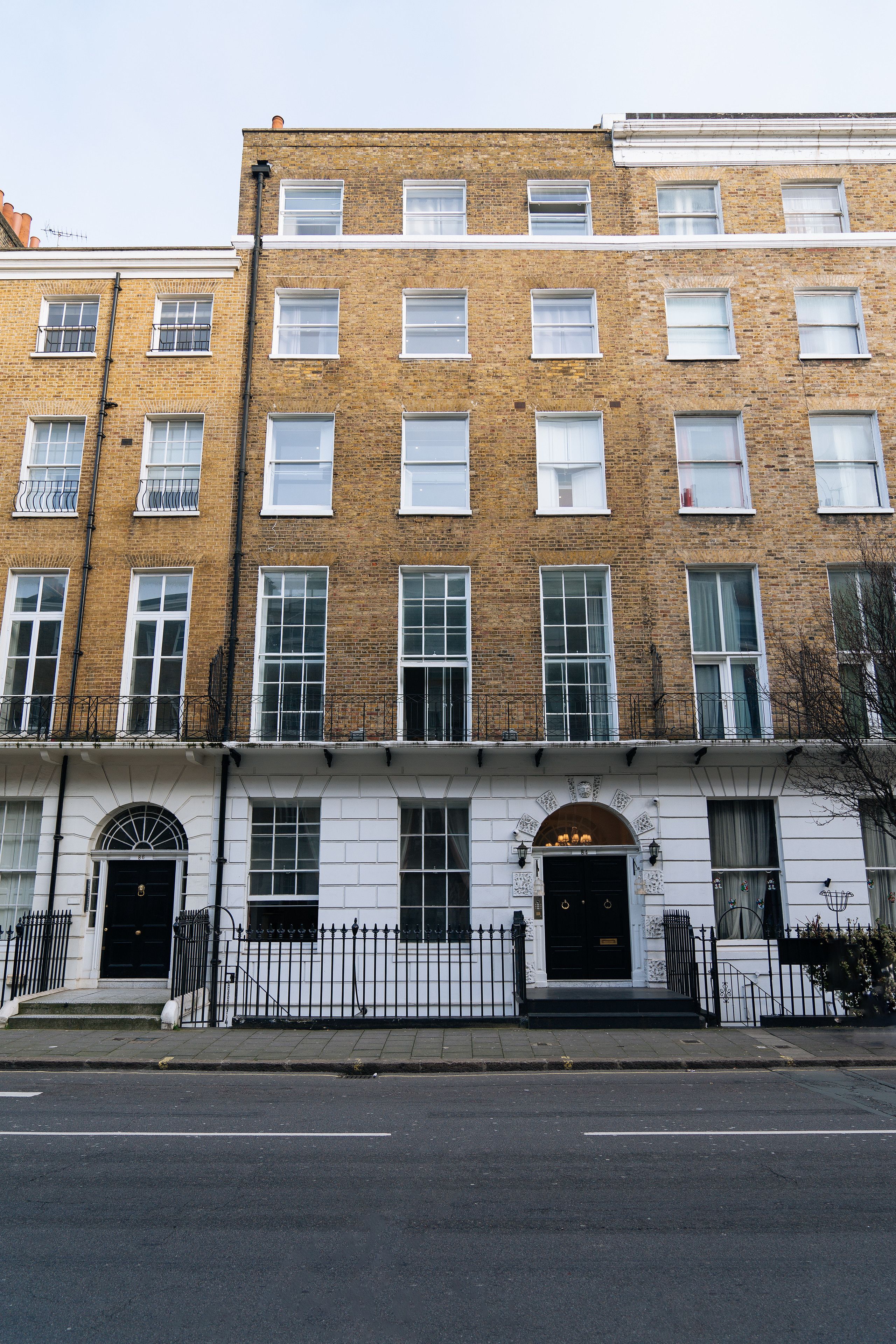 A multi-story brick building with white-framed windows and a black front door.