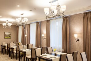 A hotel dining area with multiple tables set for dining, elegant chandeliers, and large windows with curtains. - West Park Hotel (Sofiivska Borschahivka)