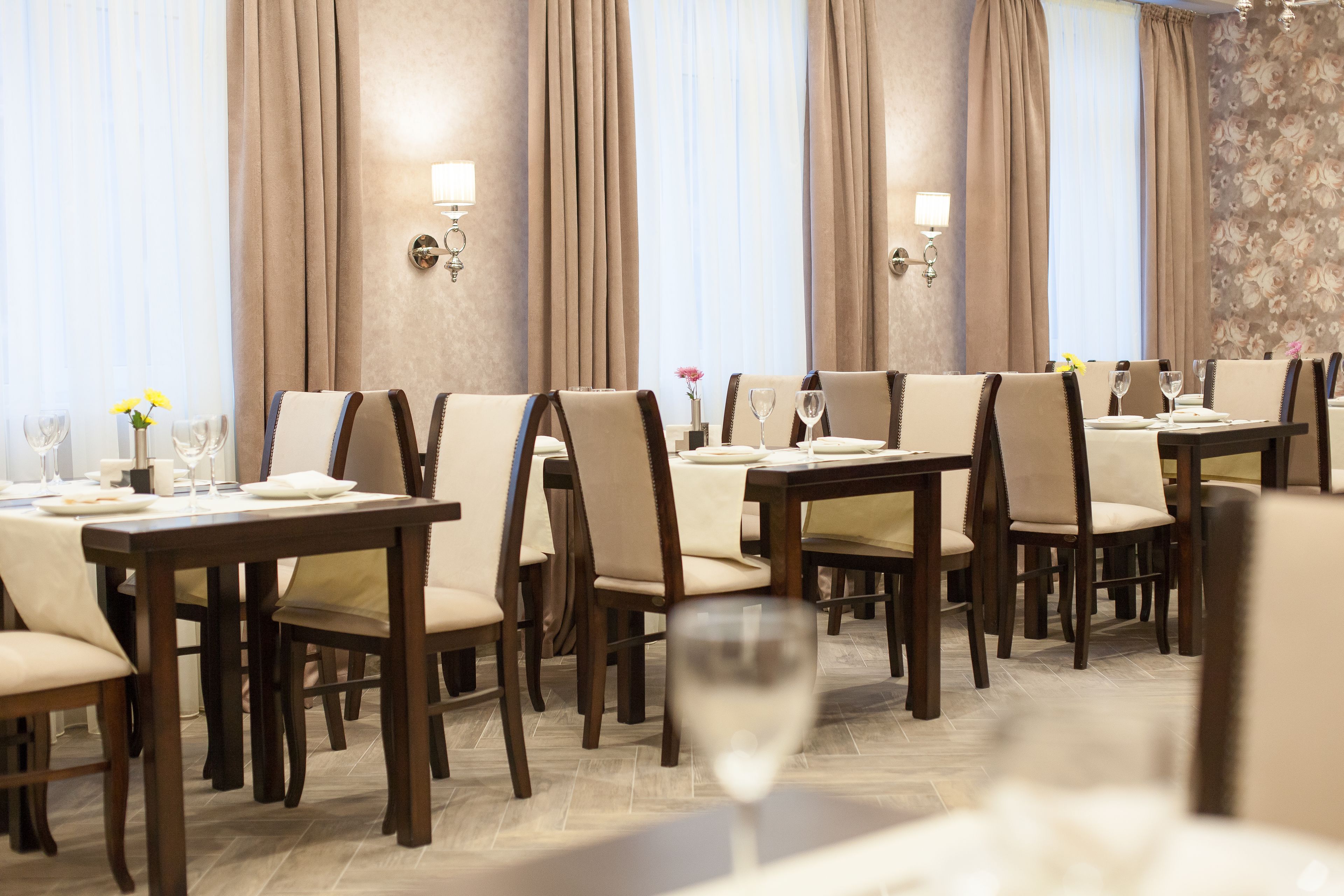 A dining area with multiple tables and chairs, each set with plates, glasses, and cutlery.