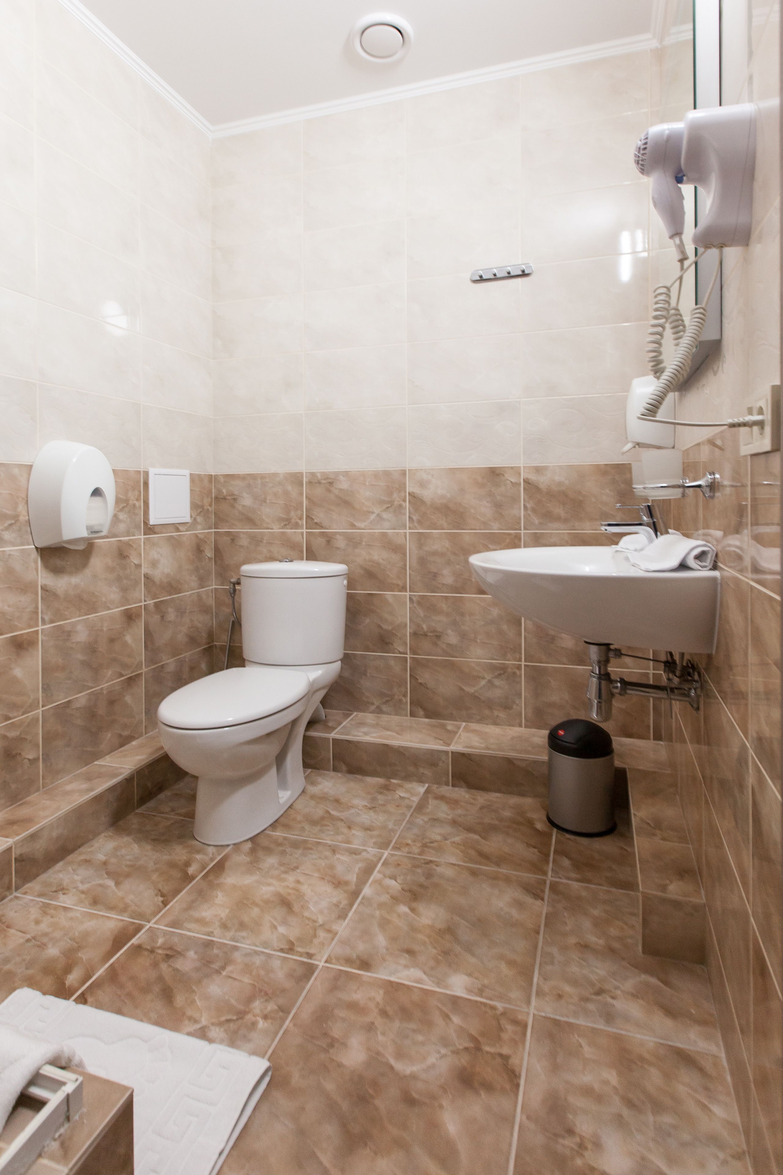 Un bagno con WC, lavandino e asciugatore di mani.