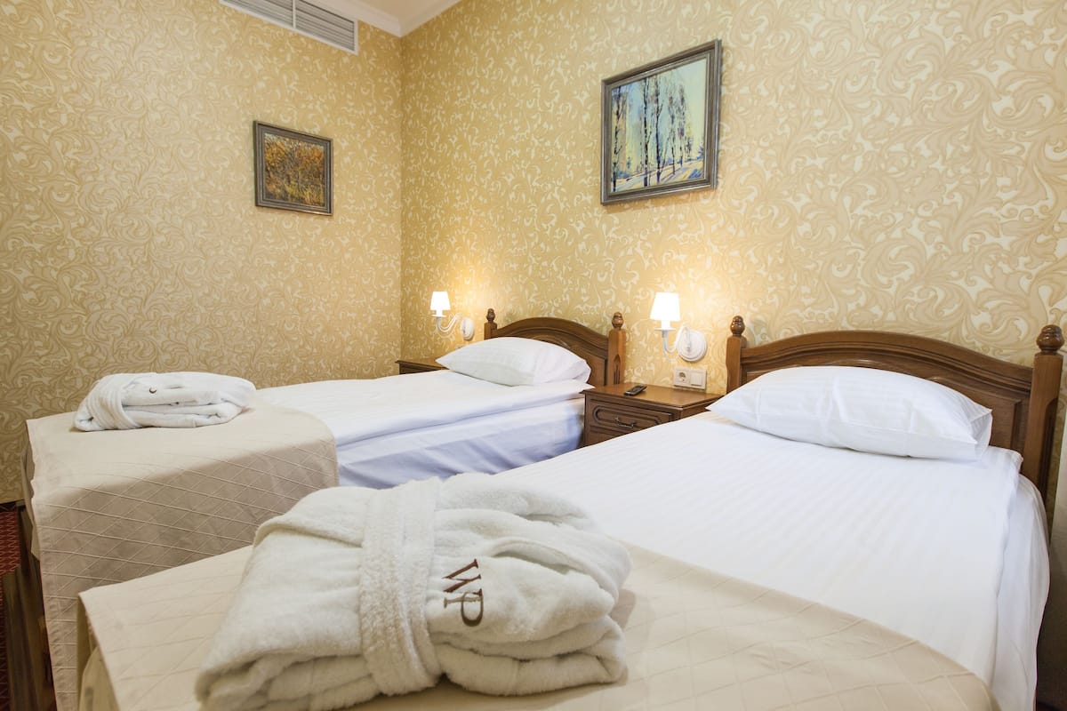 A hotel room with two beds, a wooden headboard, a telephone, and a painting on the wall.