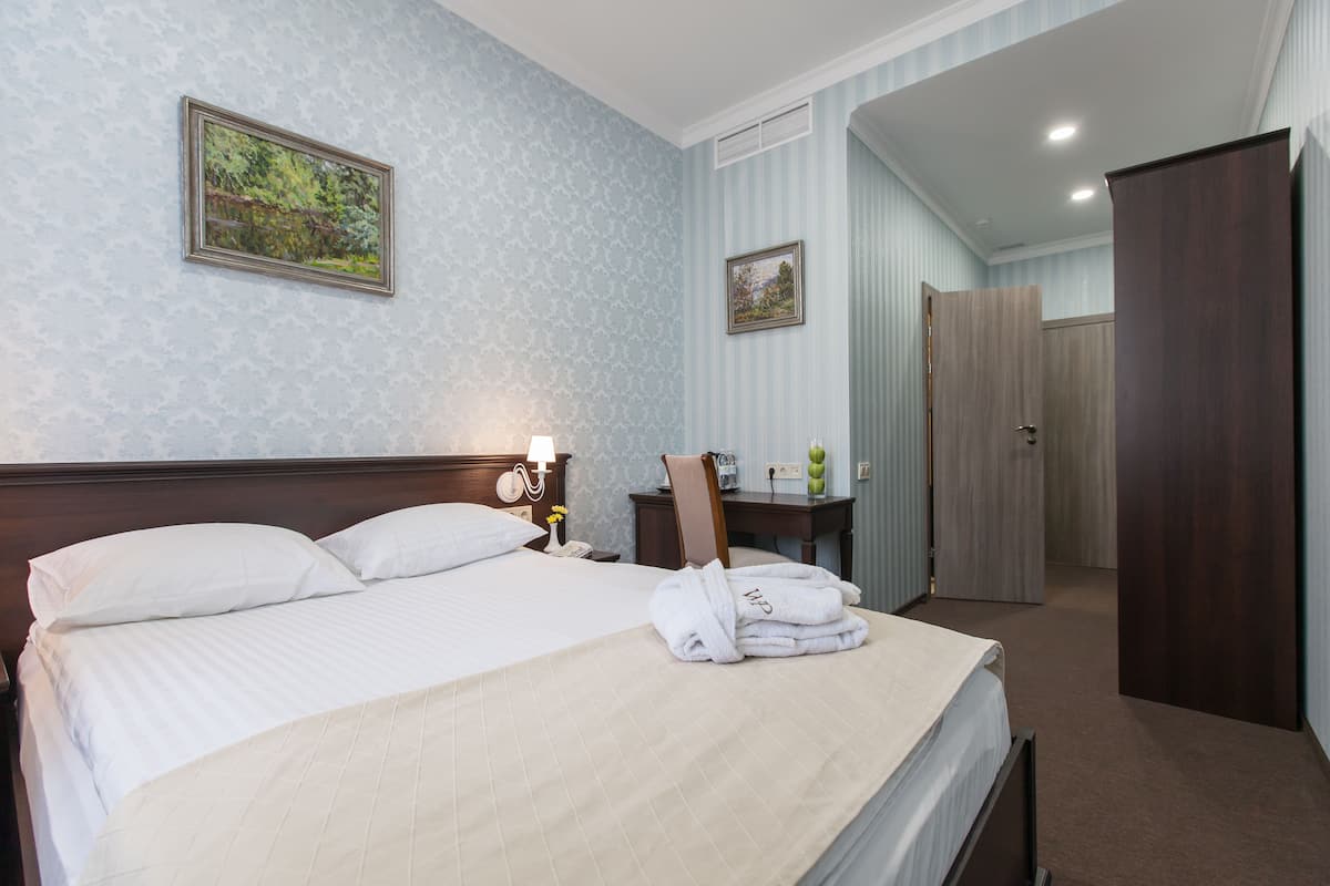 A hotel room with a bed, a nightstand, a mirror, a dresser, and a door.
