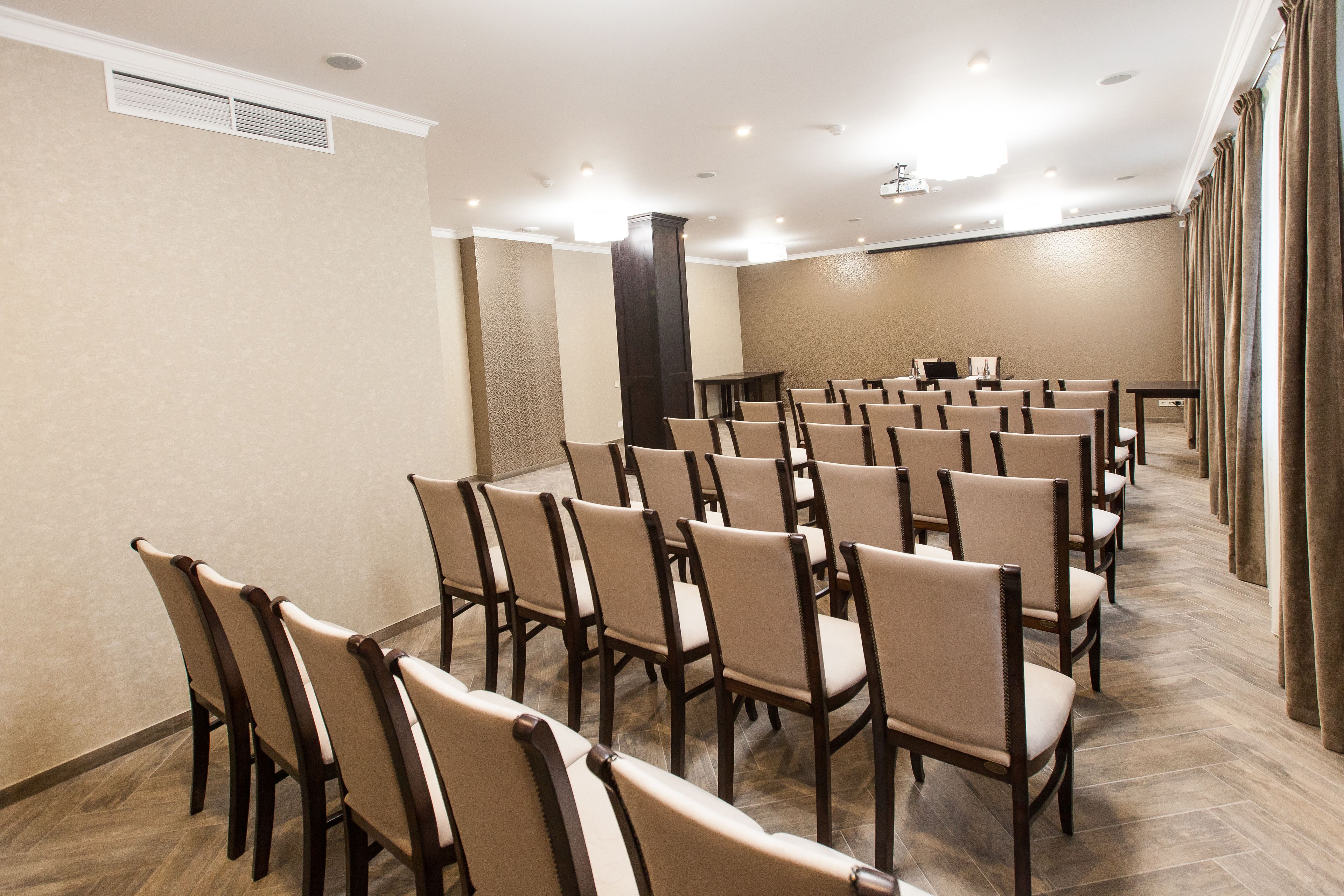 Un salón de conferencias con filas de sillas, un atril y suelo alfombrado.