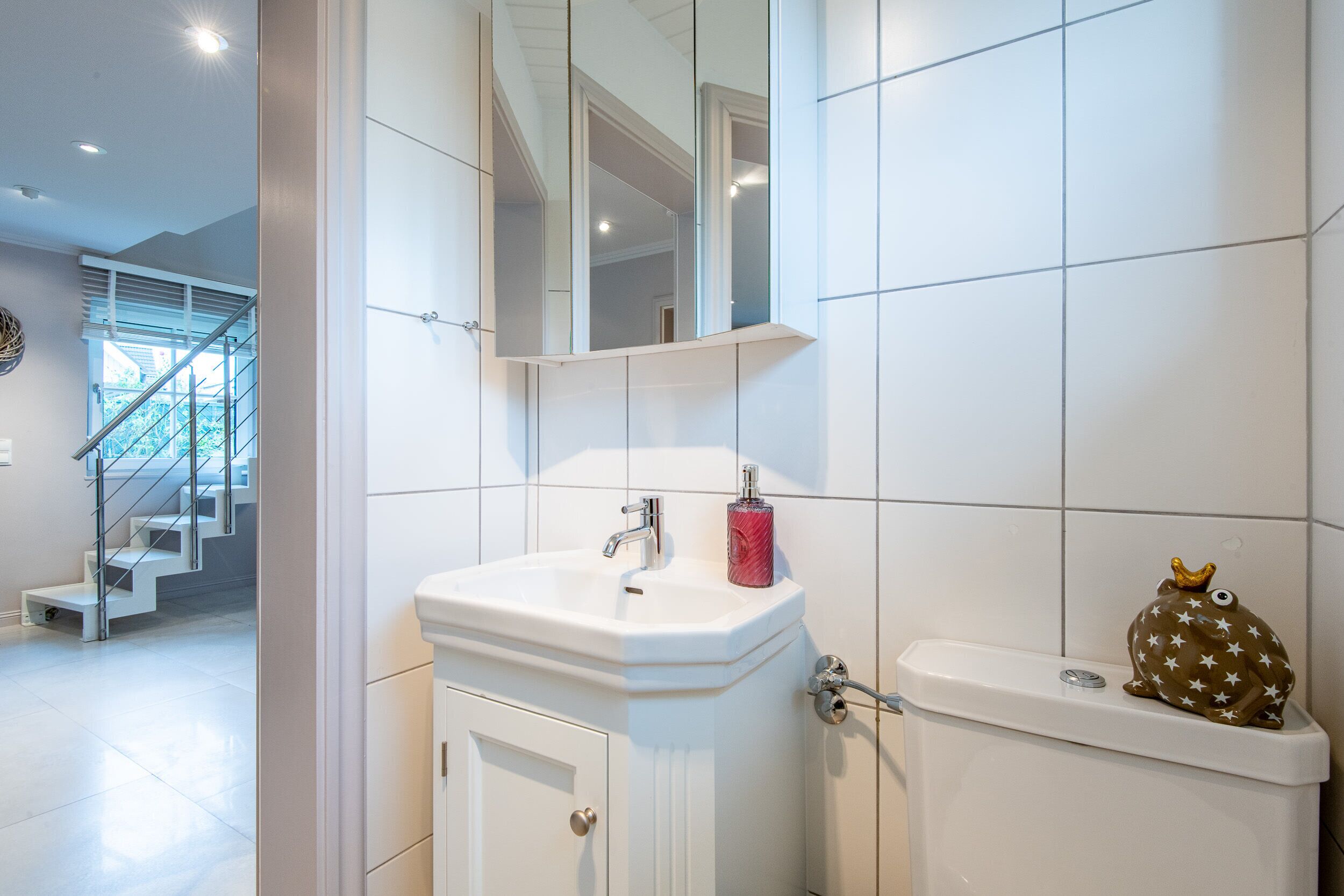 A bathroom with a white sink, mirror, and toilet.
