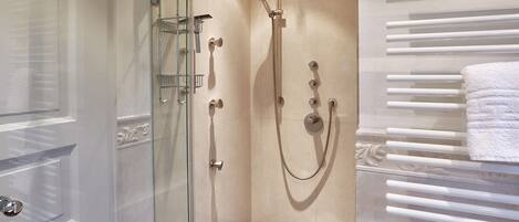 Un baño moderno con ducha de vidrio, toallero en la pared y barra de toallas con calefacción.