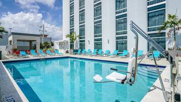 Una piscina al aire libre, sombrillas, sillones reclinables de piscina