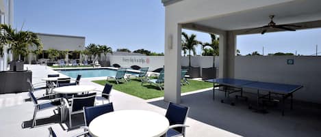 An outdoor patio area with tables and chairs, a pool, and a sign that reads "Every day a trip."
