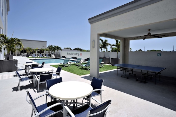 Un patio al aire libre con mesas y sillas, una piscina y un letrero que dice 'Every day a trip'.