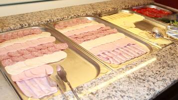 Un bufé con diferentes carnes y quesos.