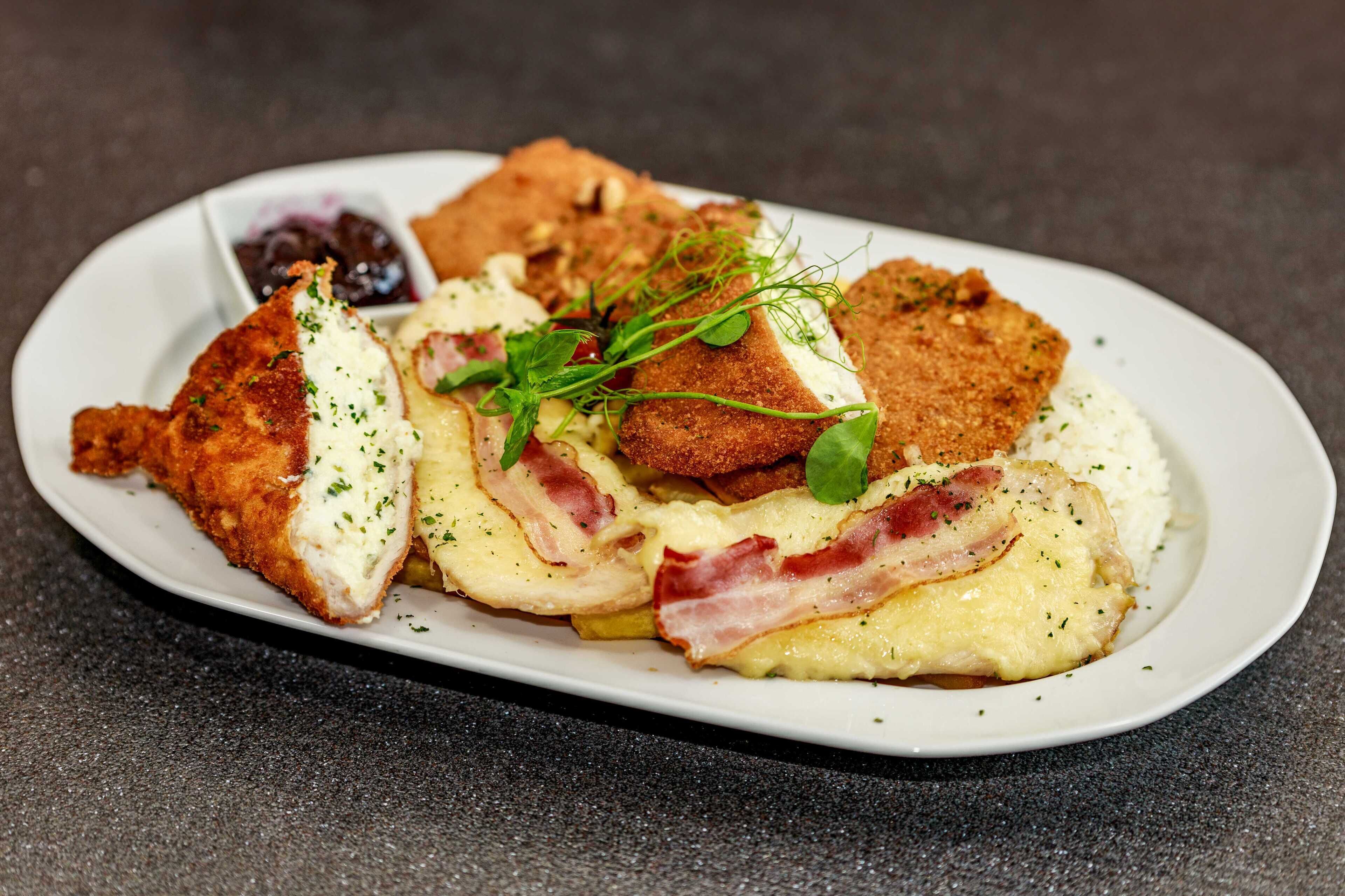 Une assiette de nourriture comprenant du poulet pané, des œufs et du bacon.