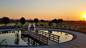 Un puente de madera sobre una superficie acuática reflectante, con un atardecer de fondo.