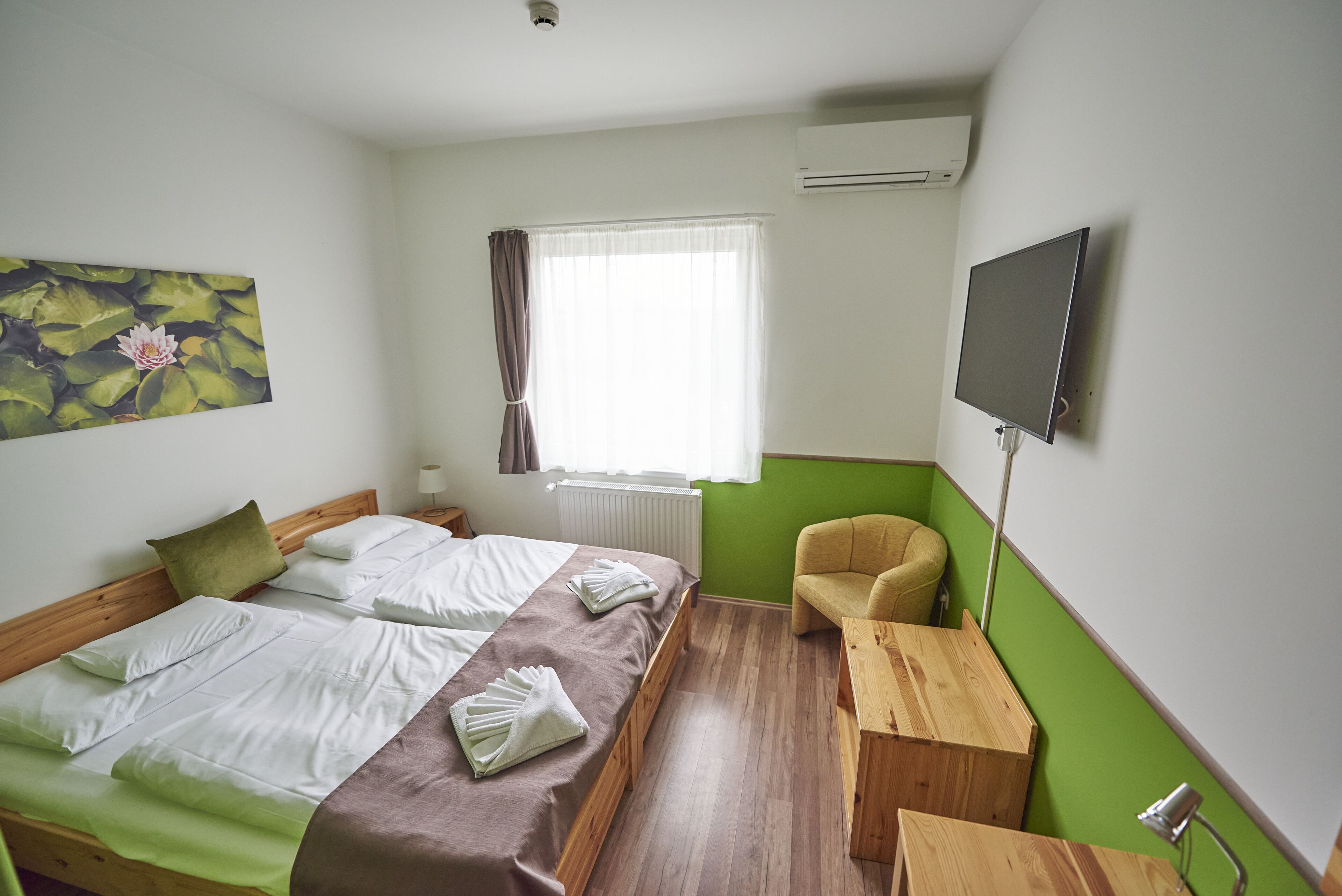 A hotel room with a bed, a chair, a TV, and a window with curtains.