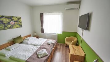 Een hotelkamer met een bed, een stoel, een televisie en een raam met gordijnen.