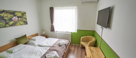 A hotel room with a bed, a chair, a TV, and a window with curtains.