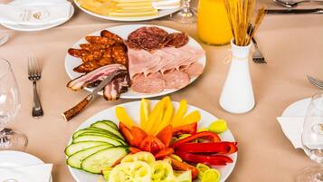 A breakfast buffet with various meats, cheeses, and fresh vegetables.