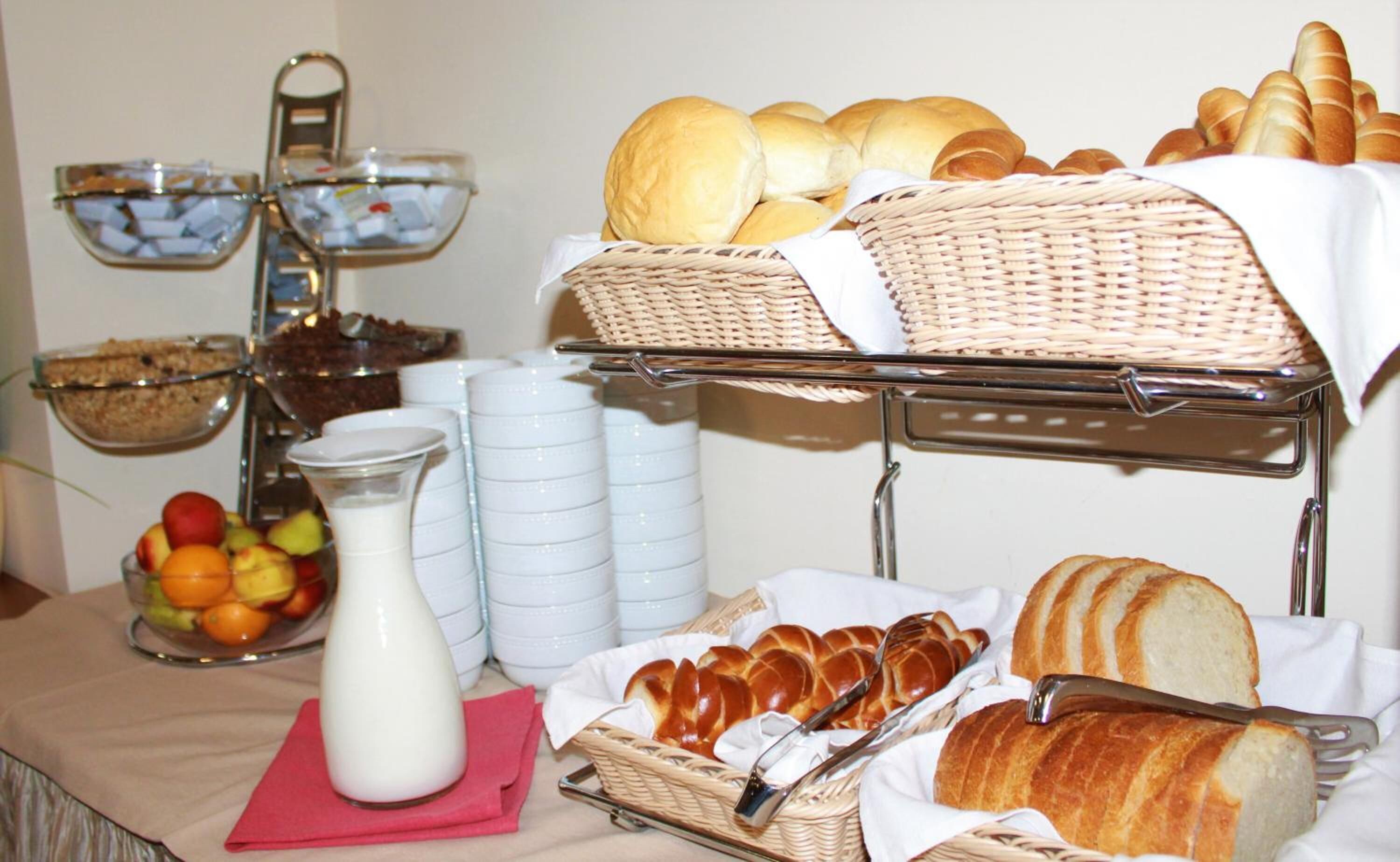 A buffet setup with bread, pastries, and a milk jug.