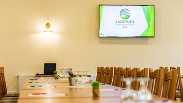 A conference room with a long table, chairs, and a screen displaying the Land-Plan Hotel & Restaurant logo.