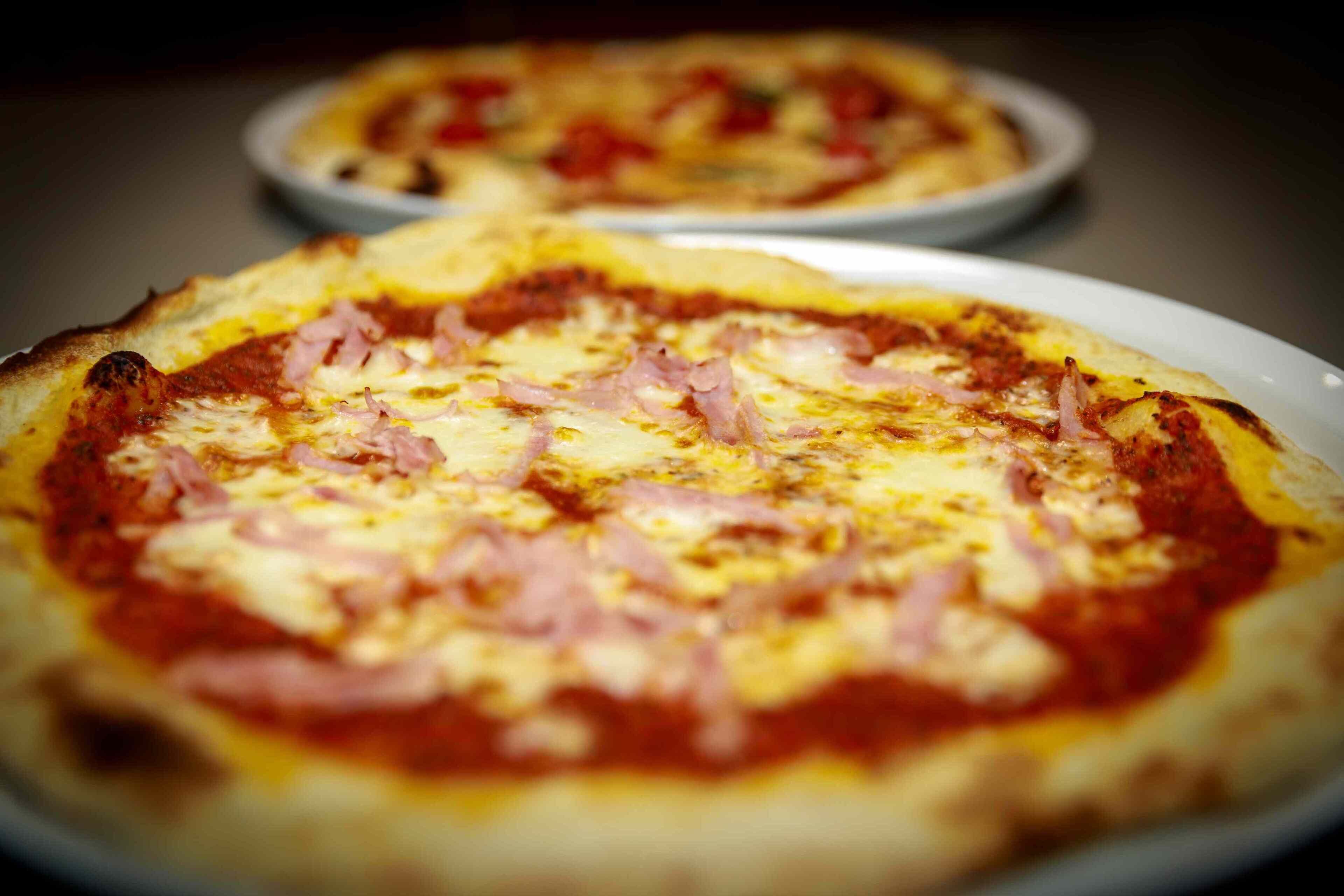Two pizzas on white plates.