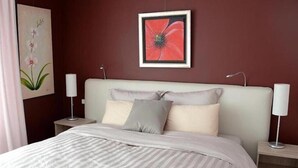 A neatly made bed with a striped bedspread, two bedside tables with lamps, and a framed picture on the wall. - Le Jardin de la Tuilerie (Pfastatt)