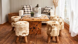 A cozy living room with a wooden coffee table, matching stools, and a sofa with plaid cushions. - ARRIVEL Pension Haus am Bach (Allershausen)