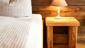 A bed with a checkered pillow and a bedside table with a lamp. - ARRIVEL Pension Haus am Bach (Allershausen)