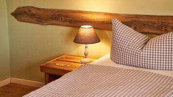 A bed with a checkered bedspread and pillows, a wooden nightstand with a lamp, and a wooden headboard.