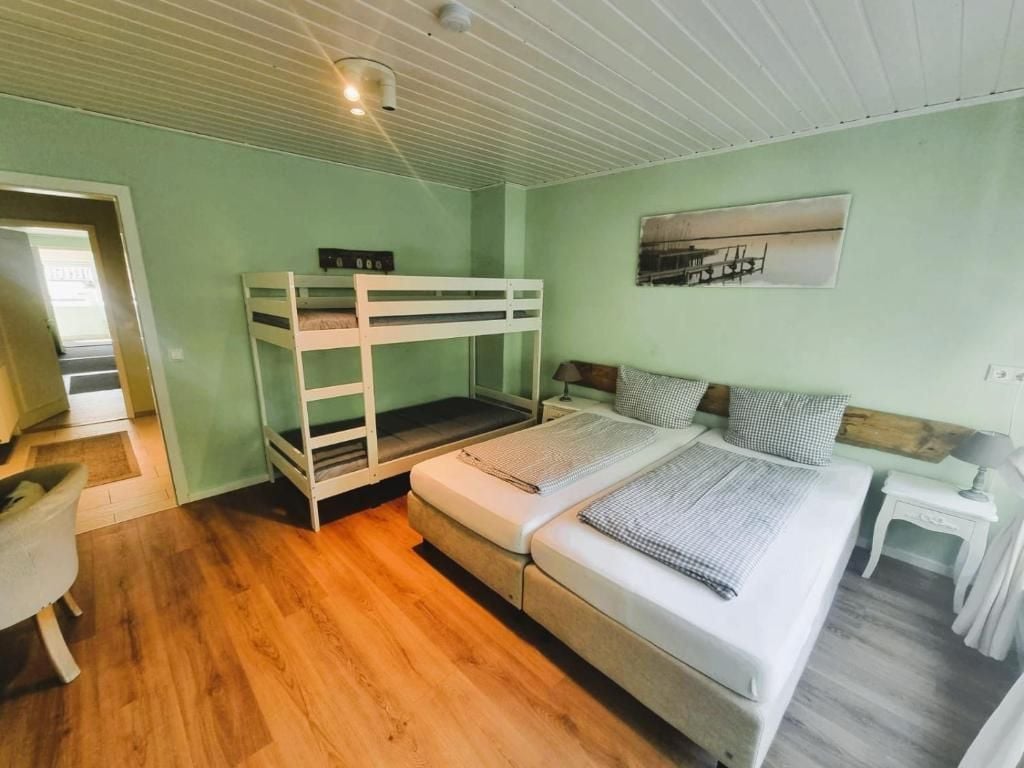 A room with bunk beds, a bedside table, a lamp, and a painting on the wall.
