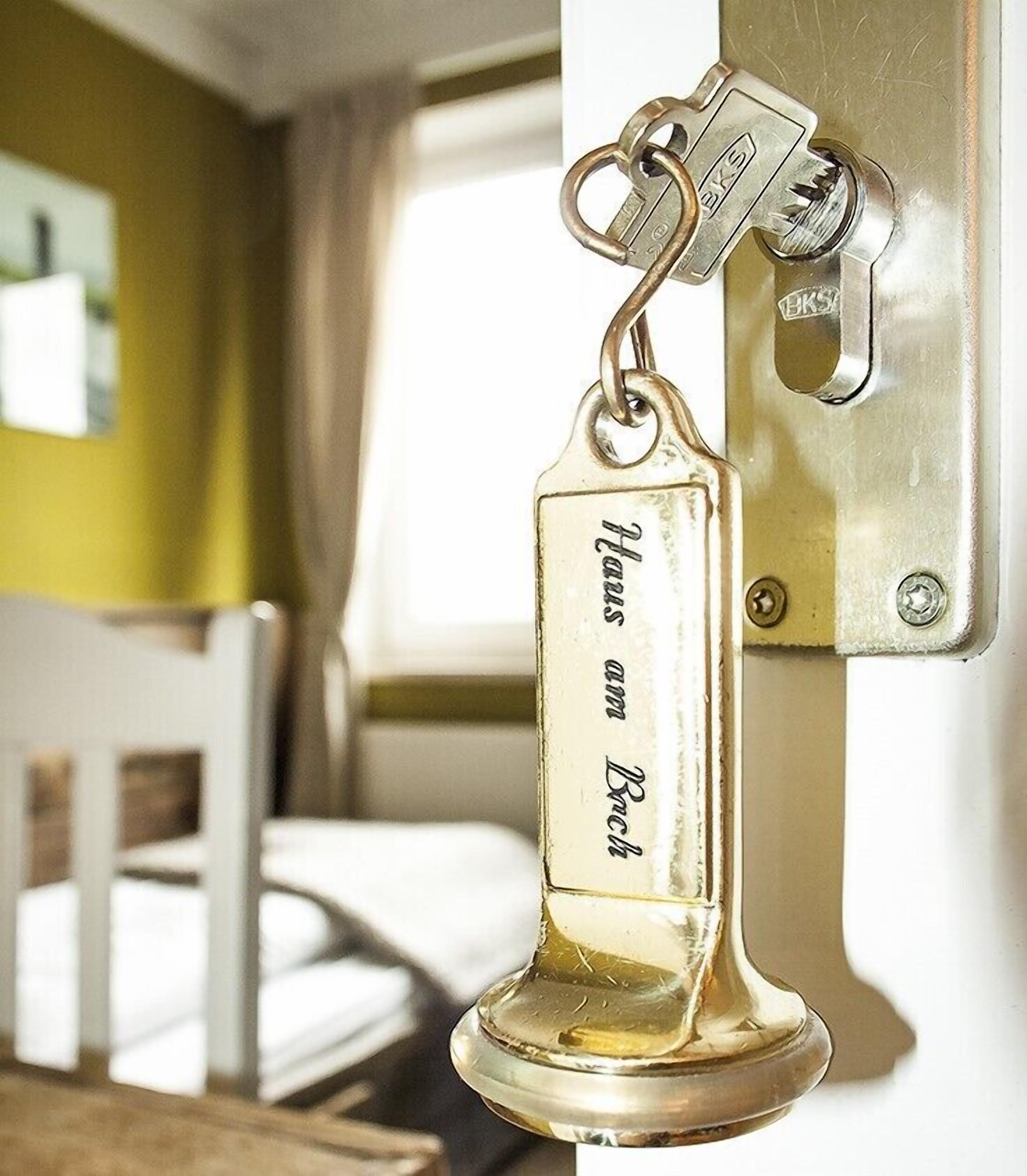 A brass keychain with the inscription "Hans am Bach" attached to a door lock.