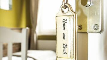 A brass keychain with the inscription "Hans am Bach" attached to a door lock.