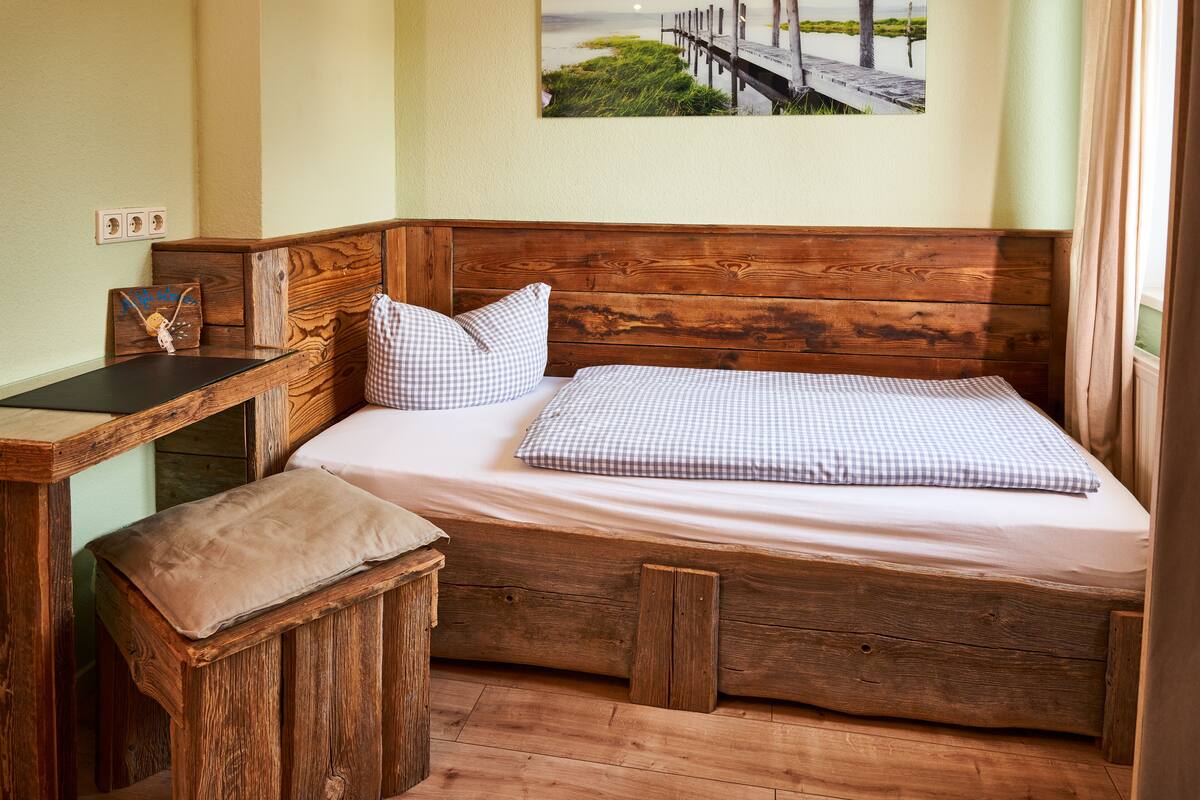Ein kleines, rustikales Schlafzimmer mit einem hölzernen Bett, einem kleinen Schreibtisch und einer Bank.