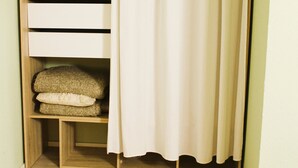 A walk-in closet with open shelving, a folded bed, and a shower curtain. - ARRIVEL Pension Haus am Bach (Allershausen)