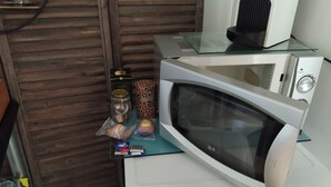 A microwave on a glass shelf with a coffee maker and a kettle on the counter. - Cielito Lindo (Montpellier)