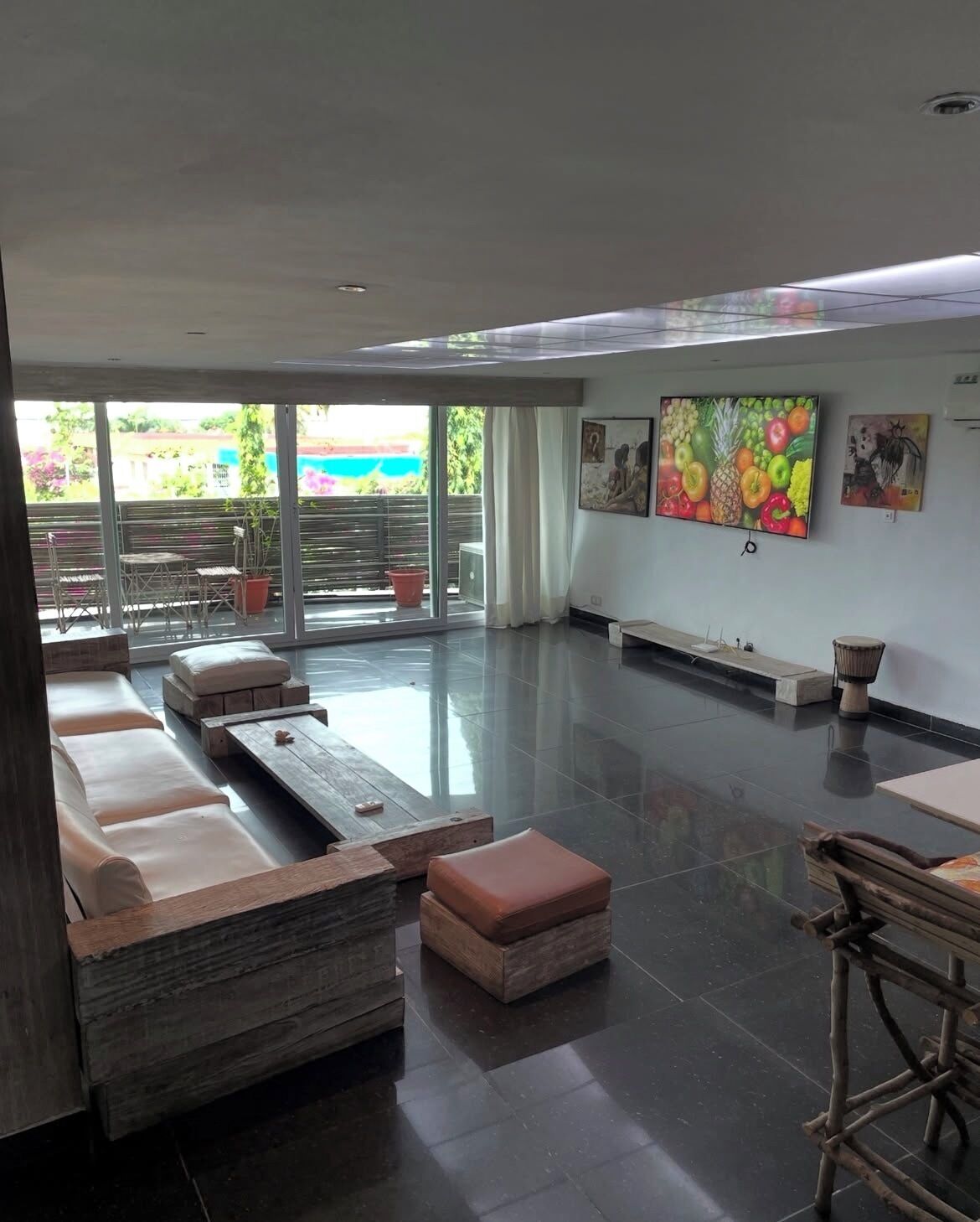 A spacious living area with a large flat-screen TV, comfortable seating, and a balcony with outdoor furniture.
