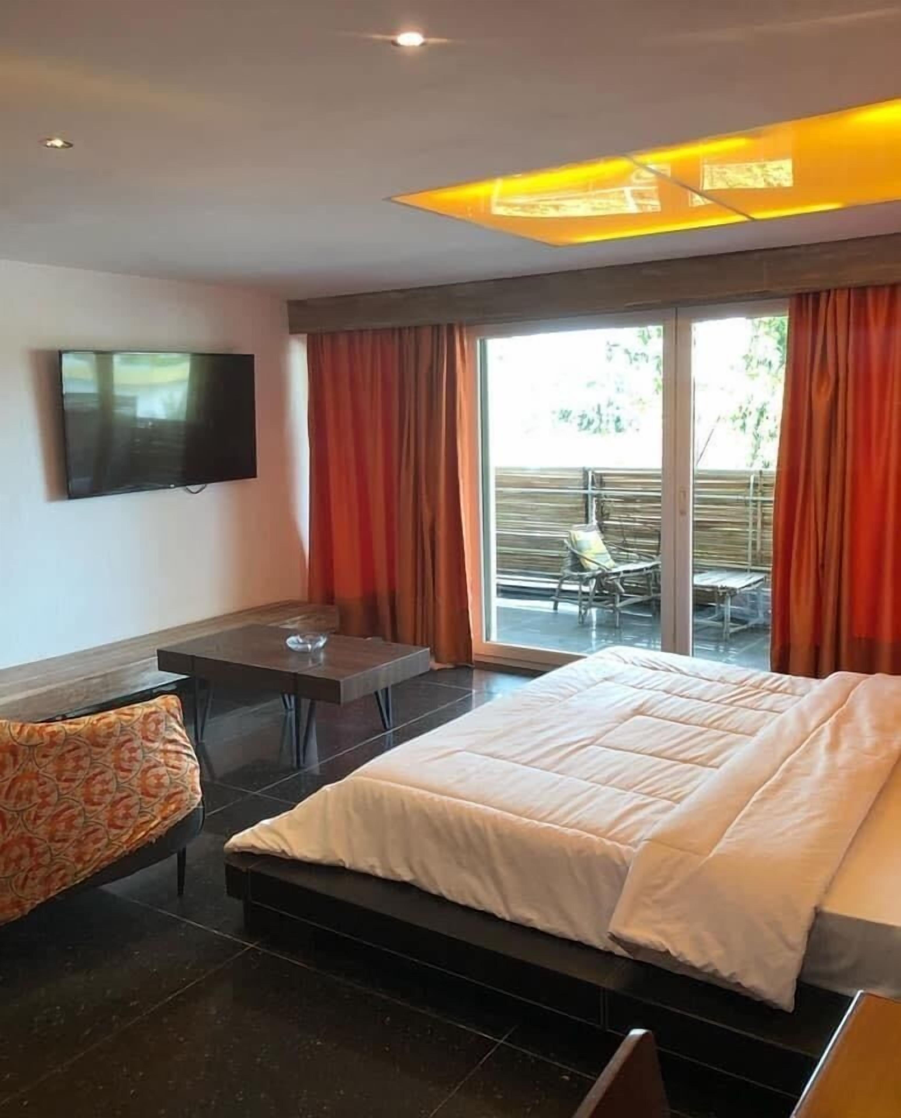 A modern hotel room with a bed, a desk, and a TV.