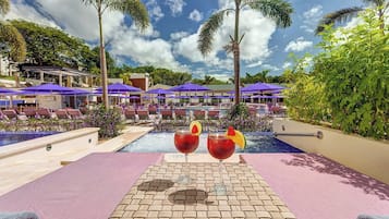 A poolside area with lounge chairs, umbrellas, and two drinks on a table.