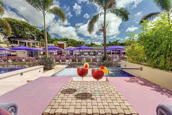 A poolside area with lounge chairs, umbrellas, and two drinks on a table. - Planet Hollywood Costa Rica by Royalton, An Autograph Collection All-Inclusive Resort (Nacascolo)