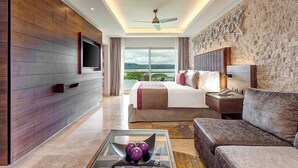 A modern hotel room with a large bed, a sofa, a TV, and a balcony with a view of the hills. - Planet Hollywood Costa Rica by Royalton, An Autograph Collection All-Inclusive Resort (Nacascolo)