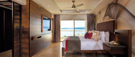 A modern hotel room with a large bed, a ceiling fan, a TV, and a view of the mountains.